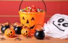 A bucket of Halloween candy surrounded by halloween decorations 
