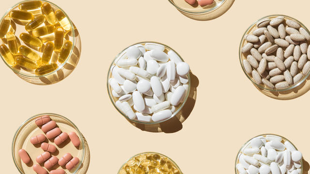 Various pills and capsules, vitamins and dietary supplements in petri dishes on a beige background. 