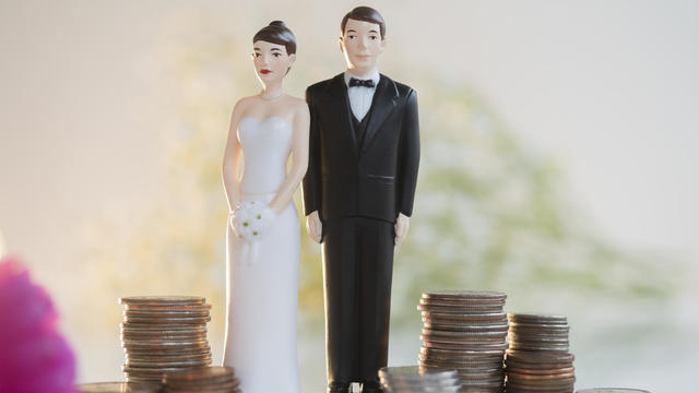 Bride and Groom cake toppers next to stacks of coins 