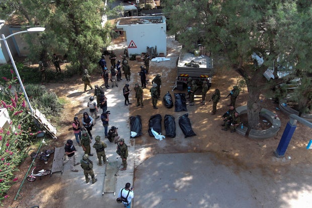 An aerial view shows covered bodies of victims of an attack by Hamas gunmen from the Gaza Strip, in kibbutz Kfar Aza, in southern Israel, October 10, 2023.