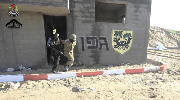 A Hamas militant in black takes a man dressed as an IDF soldier hostage in a training exercise video released in December