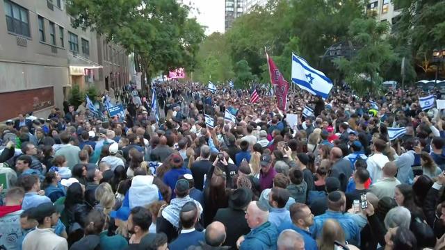 Hundreds of people, some holding Israeli flags, fill New York City streets. 