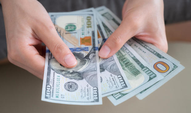 Close up of someone hands holding and counting American dollar banknotes in her hand. 