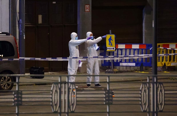 Belgian police officers from the forensic service search for evidence in a street after two people were killed during a shooting in Brussels on October 16, 2023.
