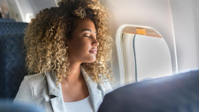 Commercial airline passenger sleeps in window seat 