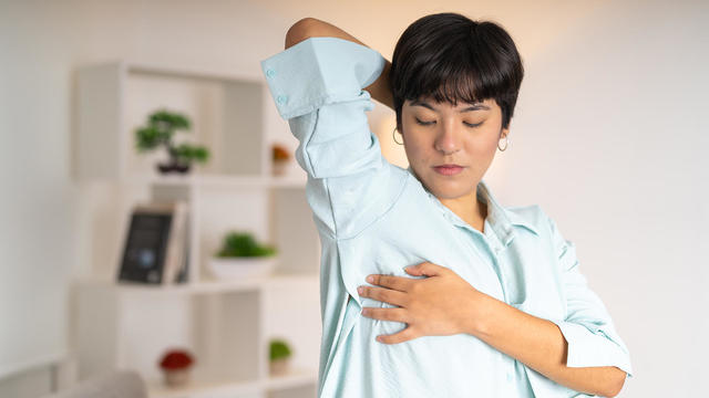 Worried woman doing self breast exam at home 