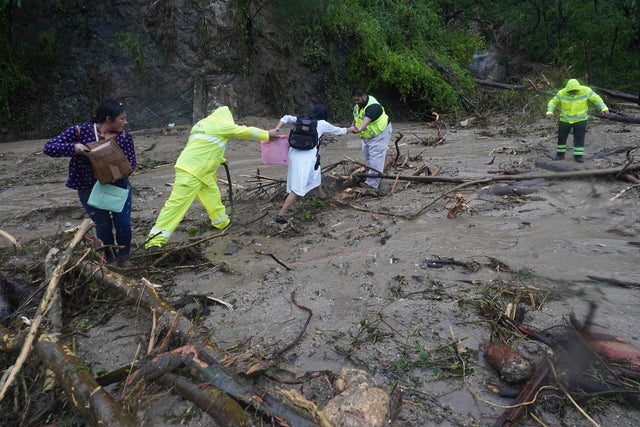 People try to cross a highway blocked by a landslide triggered by Hurricane Otis near Acapulco, Mexico 