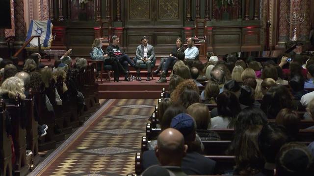 A group of individuals sit in the front of Central Synagogue. 