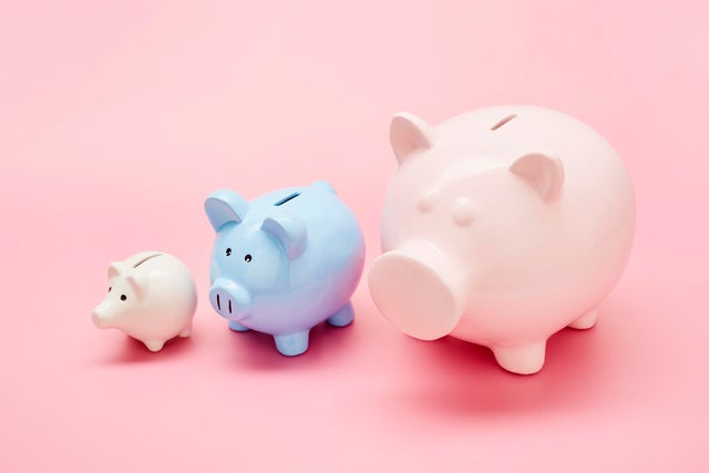 Still life of differently sized white, blue and pink piggy banks in ascending size order on pink background