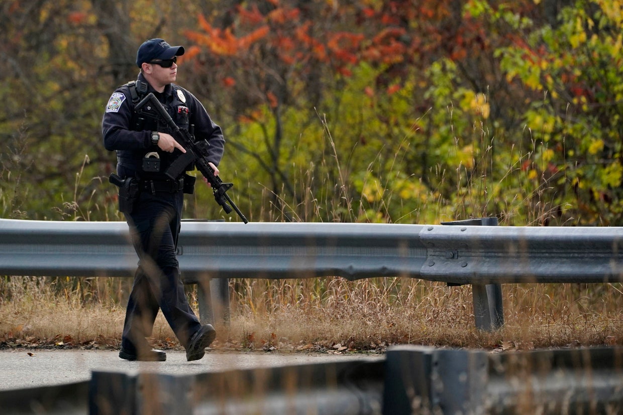 A police officer walks along a rural road during a manhunt for the Maine mass shooting suspect, Oct. 26, 2023, in Lisbon, Maine. 