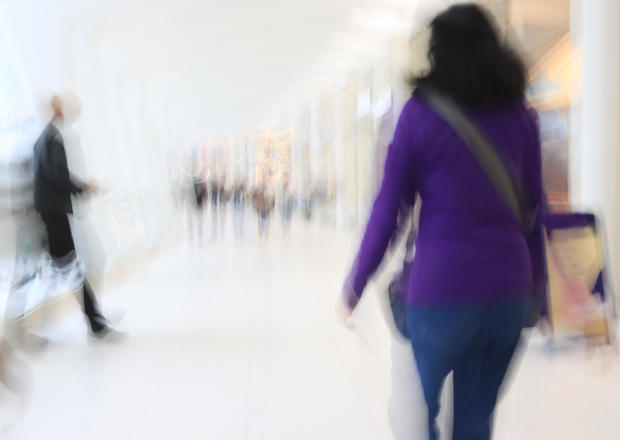 Motion blur showing woman in purple walking inside a shopping mall 
