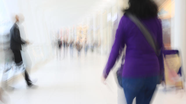Motion blur showing woman in purple walking inside a shopping mall 