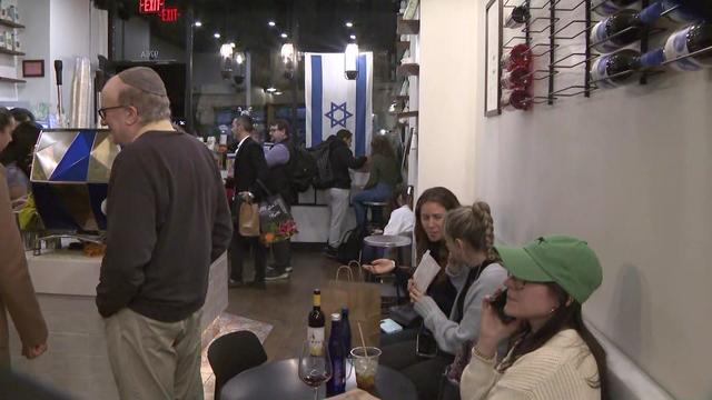 Customers fill a cafe that has an Israeli flag hanging in the window. 