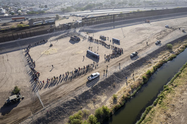 As seen from an aerial view, immigrants line up to be transported and processed by U.S. Border Patrol agents at the U.S.-Mexico border on May 12, 2023, in El Paso, Texas.  