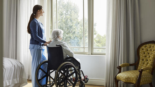 Caregiver with senior woman looking through window 
