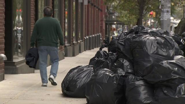 A large pile of garbage bags on a street in New York City. 