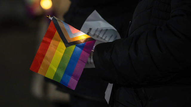 A woman holds a Pride flag during a vigil 