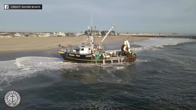 A large fishing boat sits on the shore of a beach in Point Pleasant Beach. 