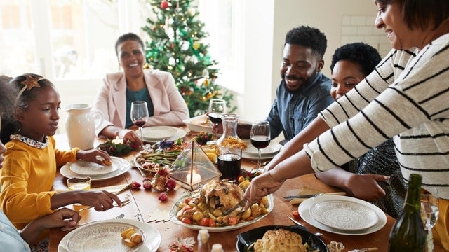 Woman cutting meat for family and friends on table