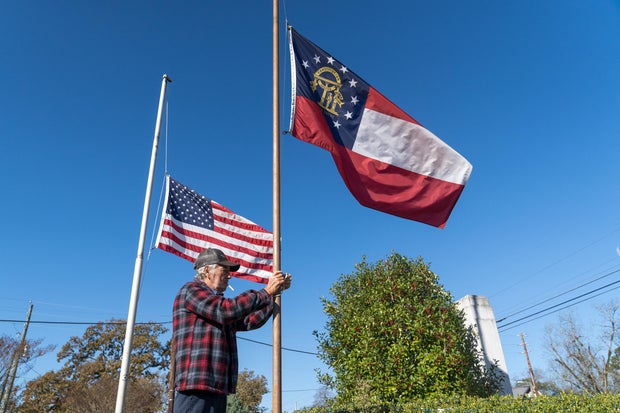 A flag is lowered by Lee Johnson as members of the Plains community come out to celebrate the life of former first lady Rosalynn Carter, on Nov. 20, 2023, in Plains, Georgia.