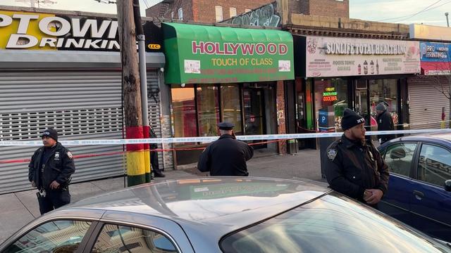 Crime scene tape blocks off the sidewalk in front of several storefronts in the Bronx. 