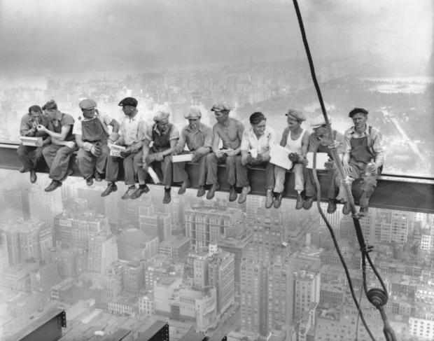 While New York's thousands rush to crowded restaurants and congested lunch counters for their noon day lunch, these intrepid steel workers atop the 70 story RCA building in Rockefeller Center get all the air and freedom they want by lunching on a steel beam with a sheer drop of over 800 feet to the street level. 