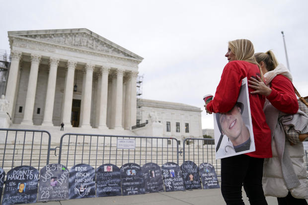 Jen Trejo holds a photo of her son Christopher as she is comforted outside the Supreme Court on Monday, Dec. 4, 2023, in Washington.  