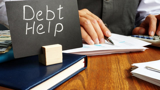 Debt help sign and working man in the office. 