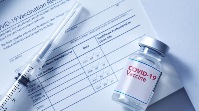 Covid-19 vaccination record card with a vial of a Covid-19 booster dose 