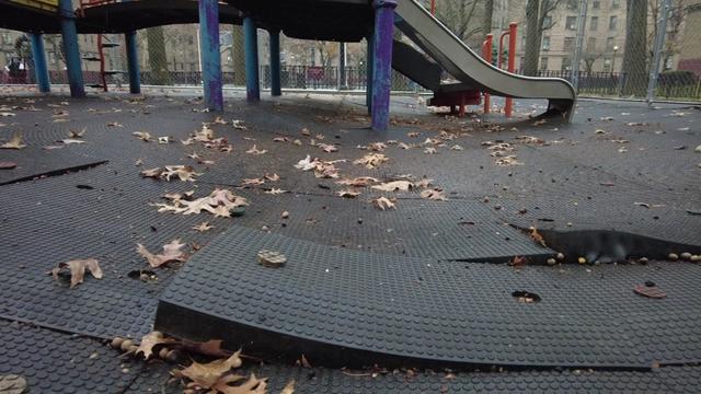 A close-up view of playground mats sloping into a sinkhole. 