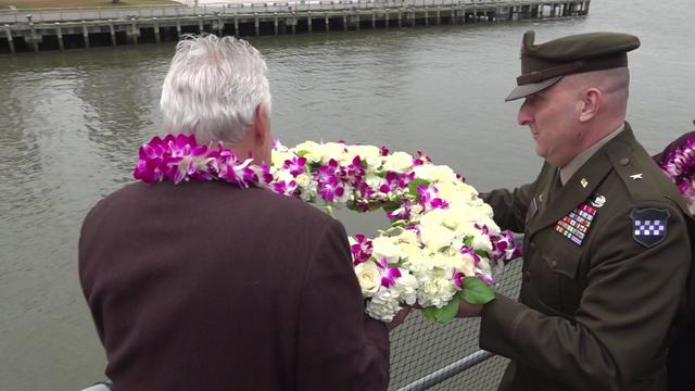 Two men hold a wreath over the side of the Intrepid. 