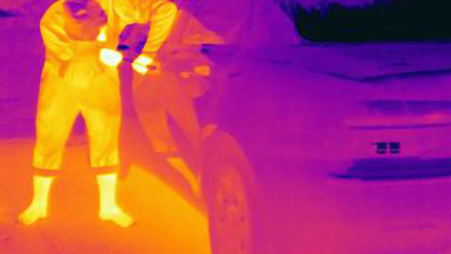 Thermal photograph of a burglar breaking into a car 