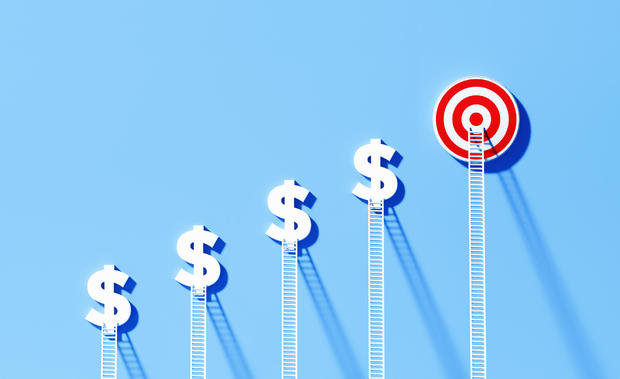 White Ladders Leaning Onto Dollar Signs And Bull's Eye Target on Blue Wall 
