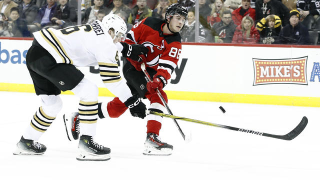 Jack Hughes #86 of the New Jersey Devils takes a shot on goal as Mason Lohrei #6 of the Boston Bruins defends during overtime at Prudential Center on December 13, 2023 in Newark, New Jersey. The Devils won 2-0 in overtime. 