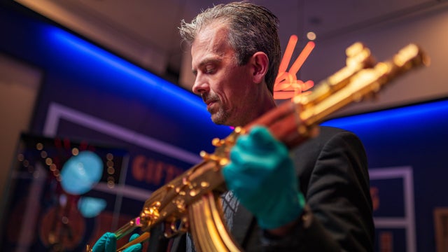 curator-jonathan-ferguson-inspects-golden-ak47-before-installation-at-reloaded-exhibition-royal-armouries-leeds.jpg