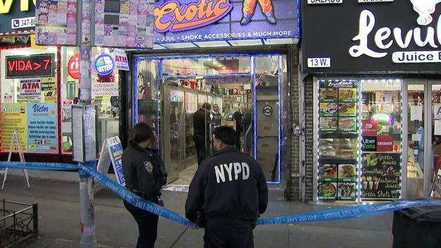 NYPD officers stand outside a Bronx smoke shop blocked off by crime scene tape. 