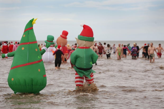 Swimmers, some in large inflatable costumes make their way into the sea on Dec. 25, 2023 in Hunstanton, England. The traditional festive swim has a history that dates back over 60 years, with swimmers wearing fancy dress and raising money for charity