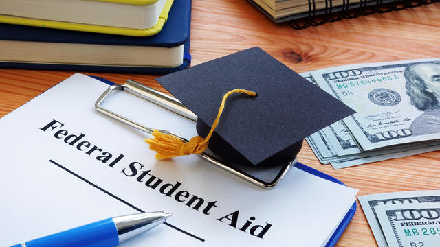 Federal student aid papers and small Square academic cap. 