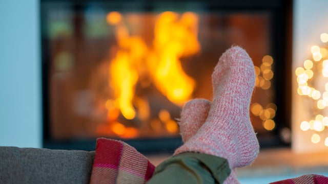 Legs of young woman wearing socks relaxing against fireplace at home 