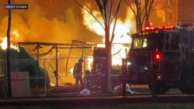 A firefighter battles large flames in an apartment building courtyard. 