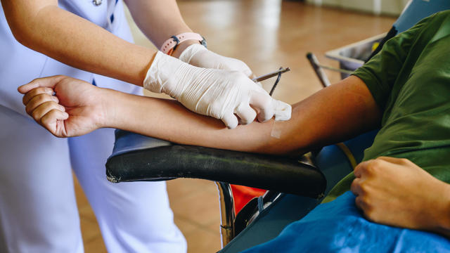 Nurse help patient to stop bleeding while donating blood. 