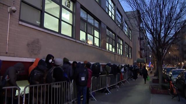 Hundreds of asylum seekers stand in a line outside an East Village building. 