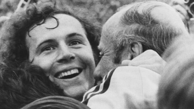 West German footballer Franz Beckenbauer beams with joy as he is embraced by coach Helmut Schon, after his team beat Holland 2-1 to win the 1974 World Cup. 