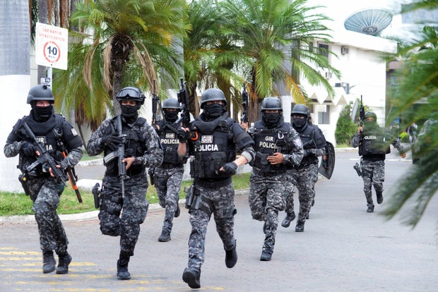An Ecuadorean police squad enters the premises of Ecuador's TC television channel after unidentified gunmen burst into the state-owned television studio live on air