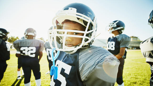 Portrait of young football player standing on field with teammates before game 