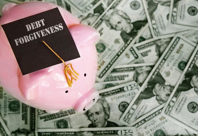 Piggy bank with Debt Forgiveness graduation cap on cash 