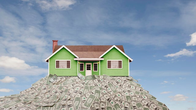House sitting on pile of dollar bills 