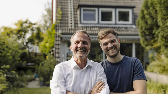 Cheerful father and son standing in backyard 