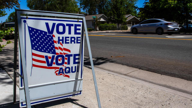 A "vote here" sign is seen on the side of a road in Reno, Nevada. 