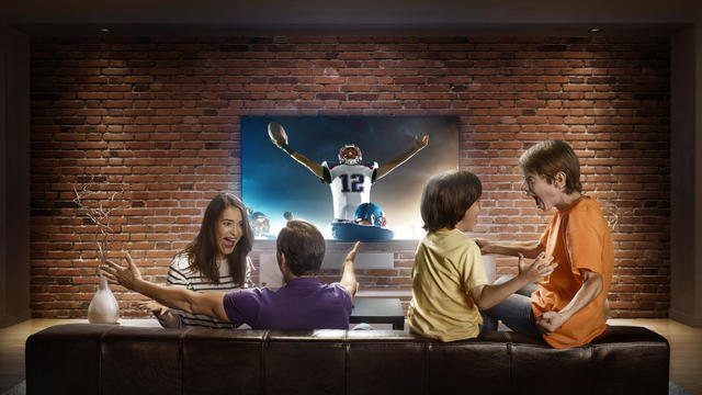 Family with children watching American football game on TV 